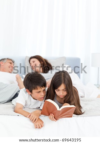 Parents talking while their children are reading on the bed