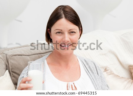 Pregnant woman drinking milk on her sofa