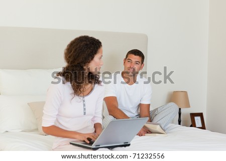 Woman working on her laptop while her husband is reading