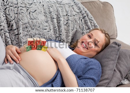 Pregnant young woman with cubes on her belly at home