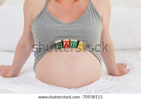 Pregnant woman with baby cubes on her belly at home