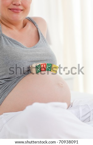 Pregnant woman with baby cubes on her belly at home