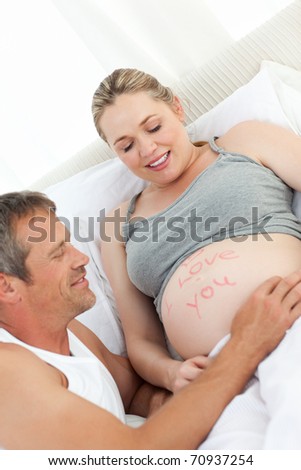 Future father touching his wife's belly at home