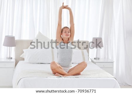 Beautiful woman practicing yoga on her bed at home