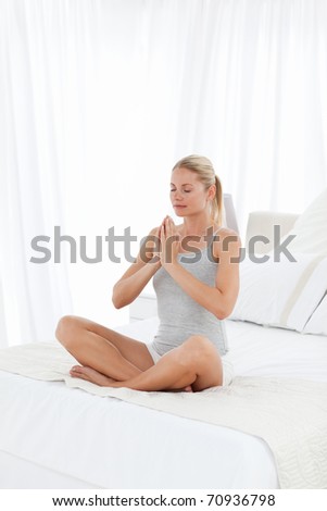 Beautiful woman practicing yoga on her bed at home