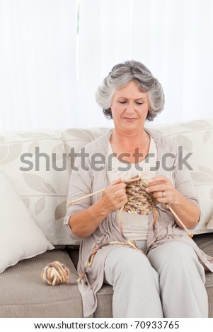 Senior knitting on her sofa at home