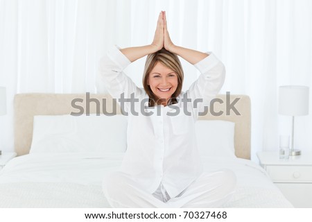 Senior practicing yoga on her bed at home