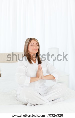 Senior practicing yoga on her bed at home