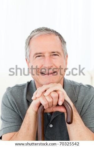 Mature man thoughtful with his walking stick on his bed at home