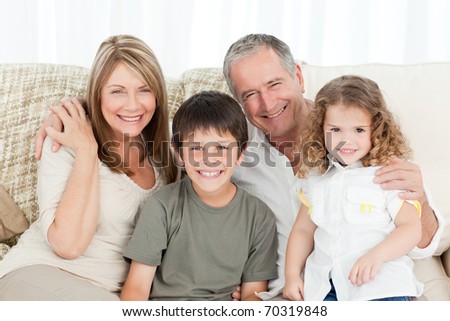A happy family on their sofa looking at the camera at home