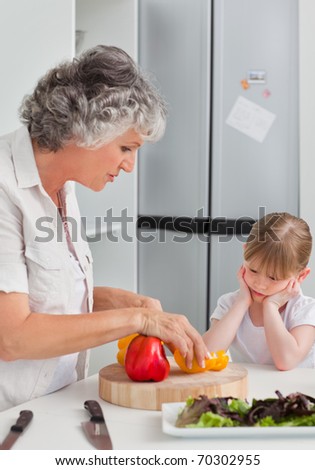 Little girl looking at her grandmother who is cooking at home