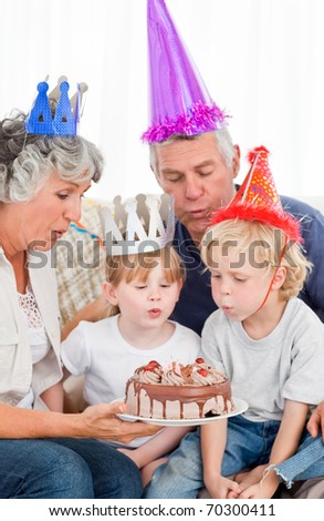 Children blowing on the birthday cake at home