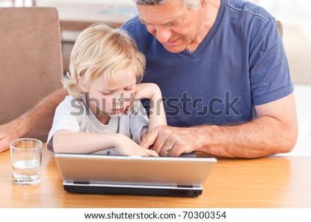 Lovely boy and his grandfather looking at their laptop at home
