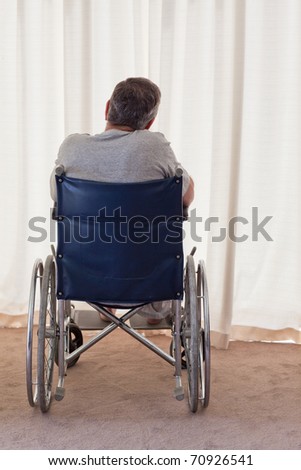Mature man in his wheelchair with his back to the camera at home