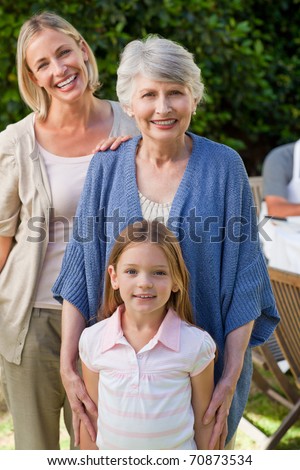 Grandmother with her daughter and grand daughter looking at the camera in the garden