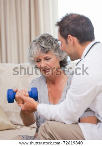 Handsome doctor helping his patient to do exercises