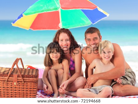 Family picnicking under a sol umbrella on the beach