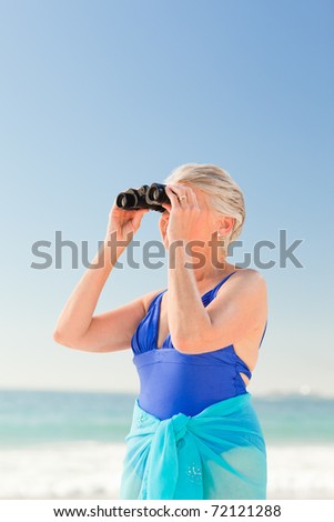 Senior woman watching bird at the beach