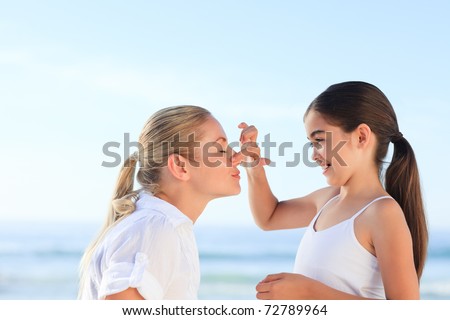 Little girl applying sun cream on her mother\'s face