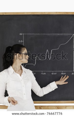 Dark-haired teacher explaining charts to students in a classroom