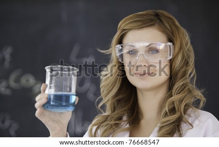 Young scientist looking at the camera while holding a beaker