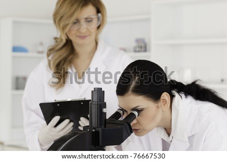 Dark-haired scientist and her assistant conducting an experiment in a lab