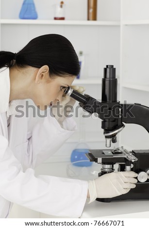 Dark-haired female looking through a microscope in a lab