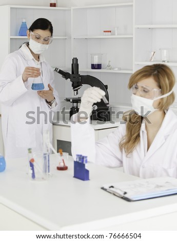 Dark-haired and blond-haired scientists conducting an experiment in a lab