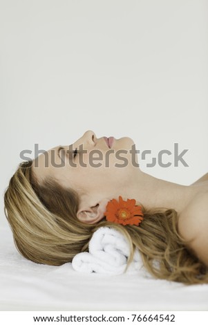 Young and attractive blond-haired woman lying down while receiving a spa treatment