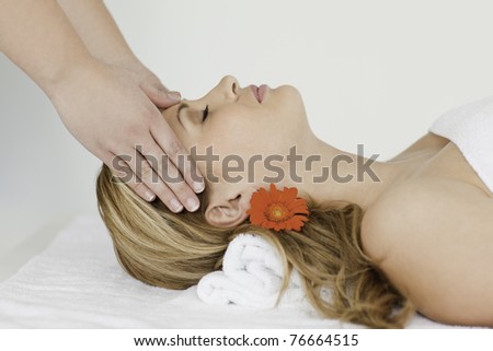 Young and lovely blond-haired woman lying down while receiving a spa treatment