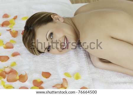 Cute blond-haired woman looking at the camera while lying down in a spa centre