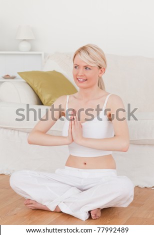 Young attractive female doing yoga in the living room in her appartement