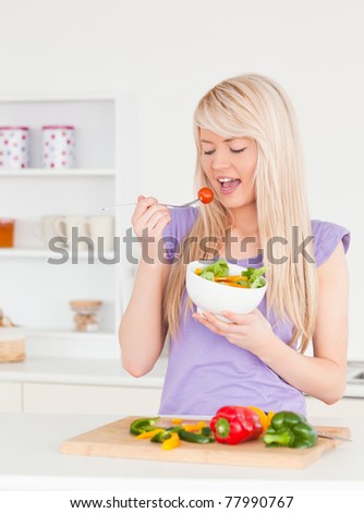 Good looking female eating her salad in the kitchen