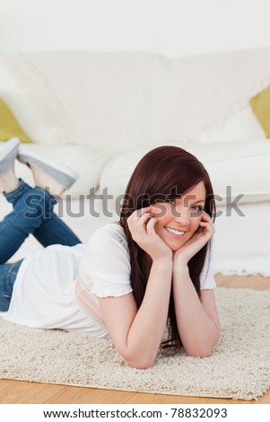 Gorgeous red-haired woman posing while lying on a carpet in the living room