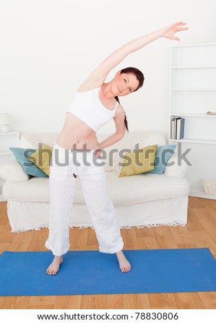 Pretty red-haired woman stretching in the living room in her apartment