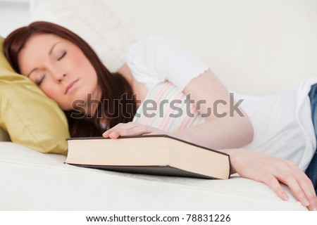 Good looking red-haired girl having a rest while studying on a sofa in the living room