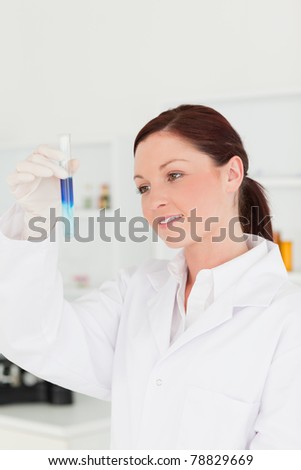 Attractive red-haired scientist looking at a test tube in a lab