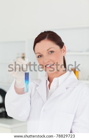 Good looking red-haired scientist looking at the camera while holding a test tube in a lab
