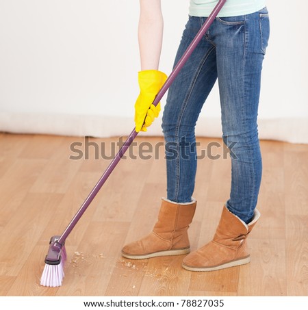 Attractive red-haired woman sweeping the floor at home