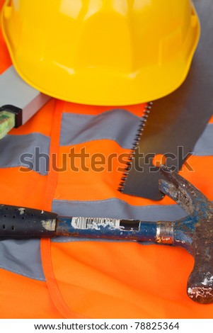 Hammer with a helmet and a saw on an orange jacket