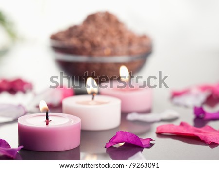 Close up of lighted candles with a brown gravel bowl and petals focus on the candles