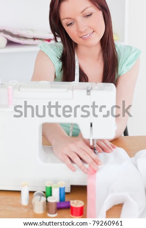 Beautiful red-haired woman using a sewing machine in her living room