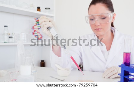 Beautiful red-haired scientist using a pipette in a lab
