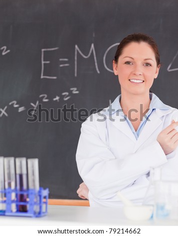 Smiling scientist standing in front of a blackboard looking at the camera
