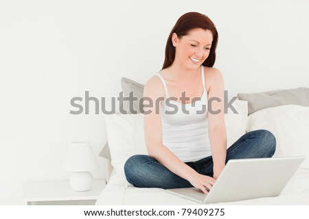 Good looking woman relaxing with her laptop in her bedroom