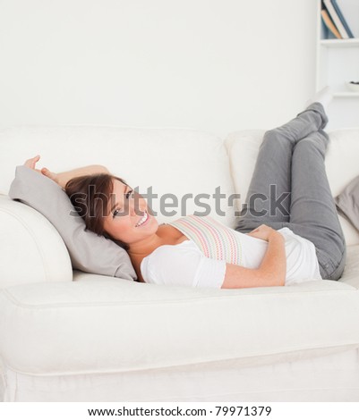 Pretty brunette woman posing while lying on a sofa in the living room