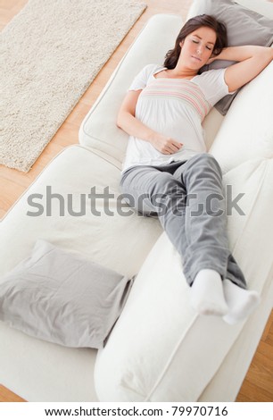 Young charming female having a rest while lying on a sofa in the living room