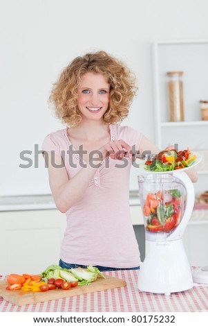 Charming blonde woman using a mixer in the kitchen in her apartment