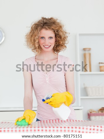 Good looking red-haired woman cleaning a cutting board in the kitchen in her apartment