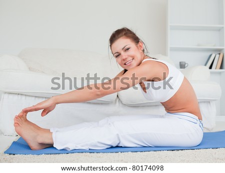 Happy brunette practicing yoga in her living room